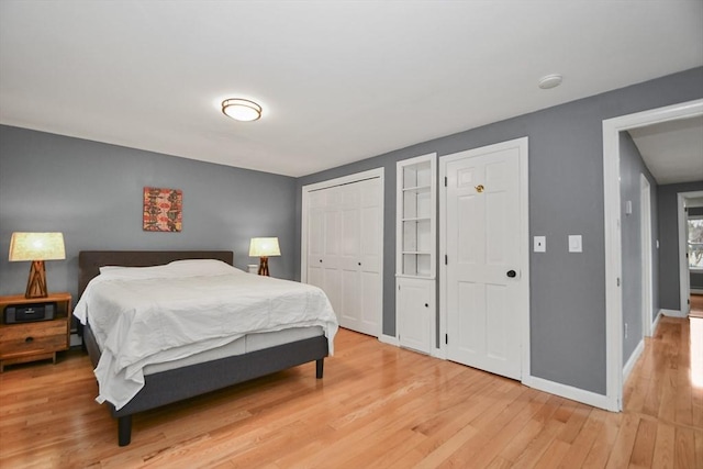 bedroom with a closet, light wood-style flooring, and baseboards