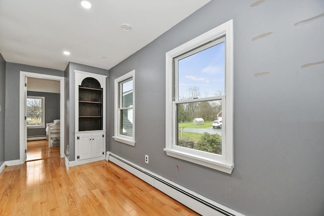 empty room featuring baseboards, a baseboard radiator, light wood-type flooring, baseboard heating, and recessed lighting