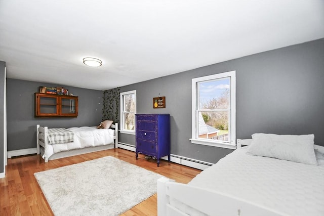 bedroom with baseboard heating, a baseboard heating unit, and light wood finished floors