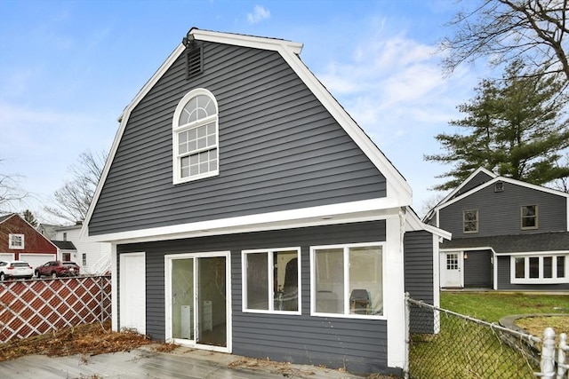 rear view of property with a gambrel roof and fence