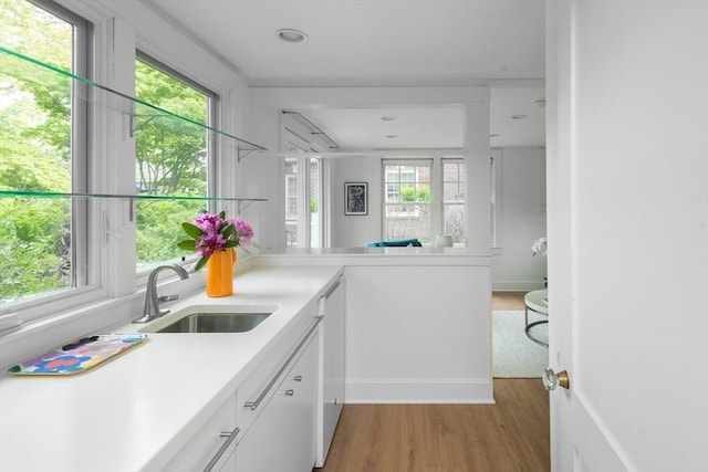 40 Stone Rd, Belmont, MA 02478 - kitchen featuring light wood finished floors, white cabinets, a sink, light countertops, and a peninsula