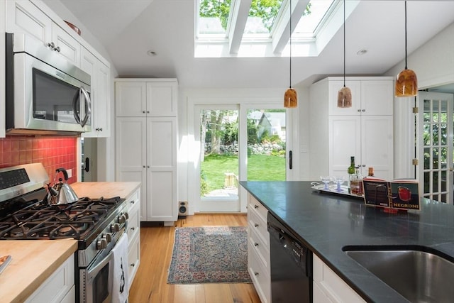 40 Stone Rd, Belmont, MA 02478 - kitchen with appliances with stainless steel finishes, a skylight, white cabinetry, light wood-style floors, and lofted ceiling