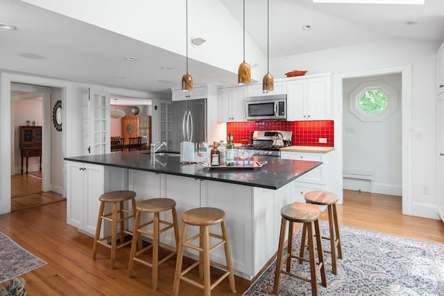 40 Stone Rd, Belmont, MA 02478 - kitchen with appliances with stainless steel finishes, light wood-type flooring, white cabinets, and a kitchen breakfast bar