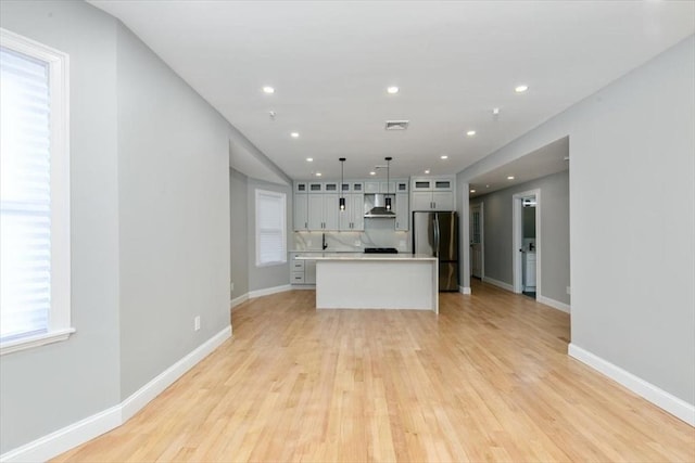 755 Boylston St Unit 2, Brookline, MA 02467 - kitchen with freestanding refrigerator, wall chimney exhaust hood, light countertops, glass insert cabinets, and light wood-style flooring