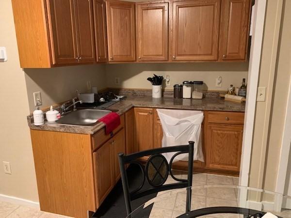 kitchen featuring a sink, brown cabinetry, light tile patterned floors, and baseboards