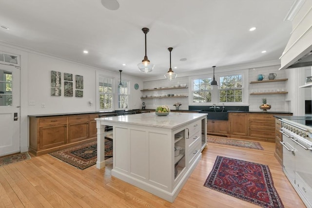 kitchen with a healthy amount of sunlight, brown cabinetry, open shelves, and crown molding