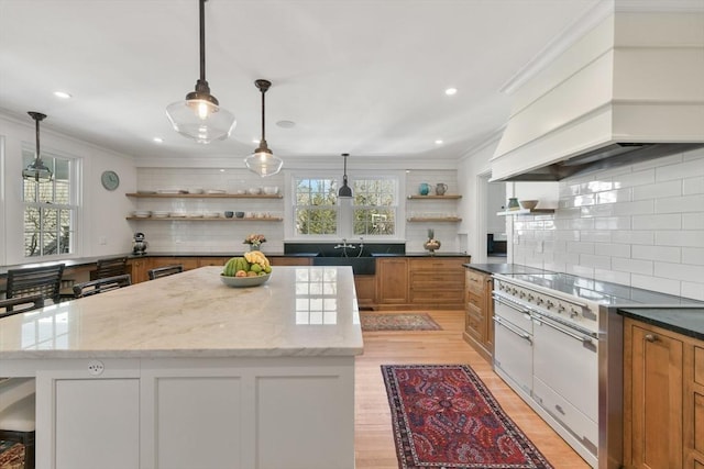 kitchen with a center island, open shelves, ornamental molding, premium range hood, and brown cabinets