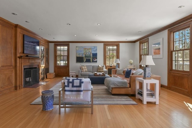 living room featuring baseboards, crown molding, recessed lighting, light wood finished floors, and a fireplace with flush hearth