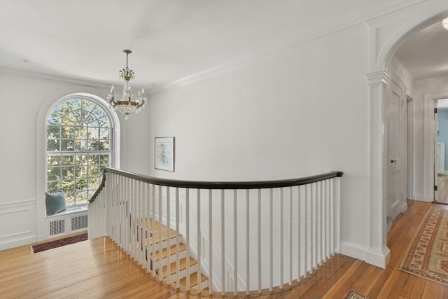 hallway featuring ornamental molding, a chandelier, an upstairs landing, hardwood / wood-style floors, and arched walkways