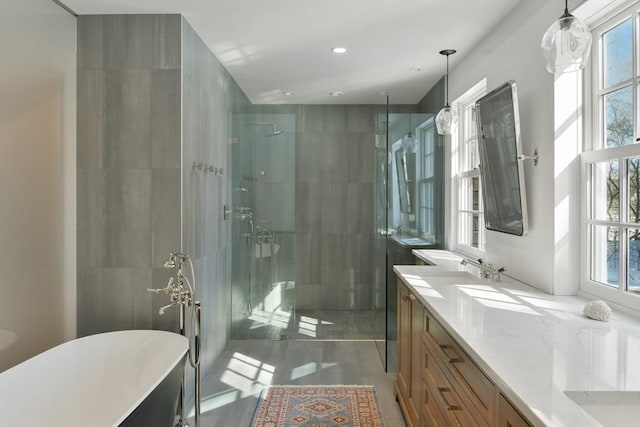bathroom featuring a freestanding bath, tiled shower, a sink, and double vanity