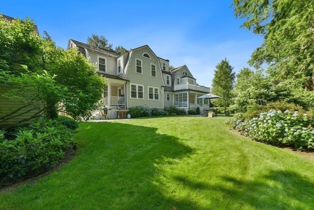 rear view of house featuring a gambrel roof, central AC unit, and a lawn