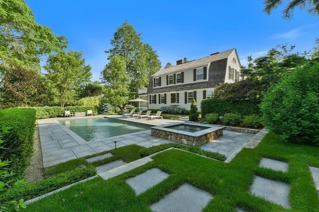 pool featuring a patio, an in ground hot tub, and a lawn
