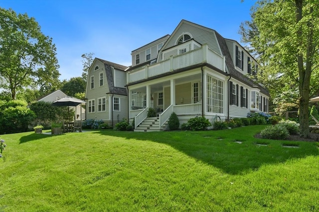 view of front of home with a front yard, a porch, and a gambrel roof