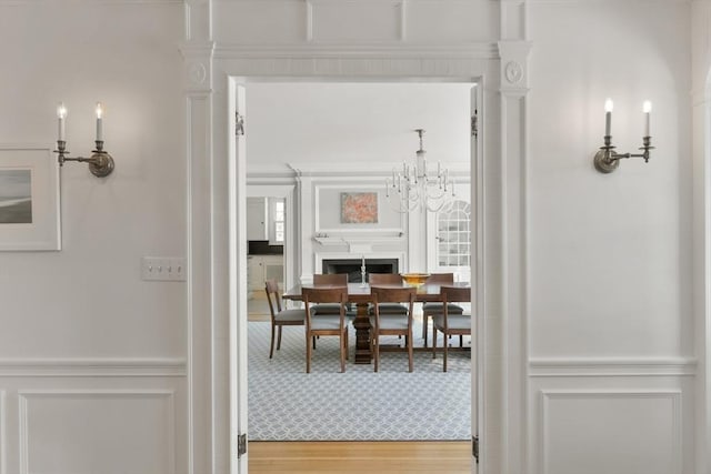 dining room with a decorative wall, wainscoting, an inviting chandelier, and wood finished floors