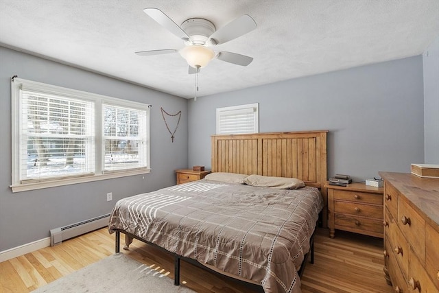 bedroom with light wood finished floors, ceiling fan, baseboards, and baseboard heating