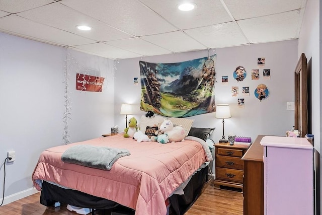 bedroom featuring baseboards, a drop ceiling, wood finished floors, and recessed lighting