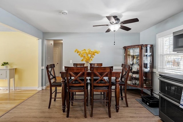 dining room with a ceiling fan, baseboards, and wood finished floors