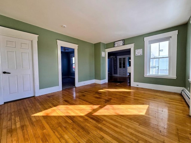 unfurnished living room featuring hardwood / wood-style flooring and baseboards