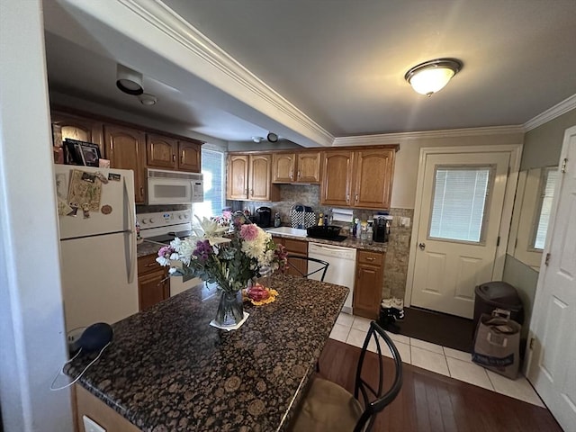 kitchen featuring white appliances, ornamental molding, decorative backsplash, light wood-style flooring, and brown cabinets
