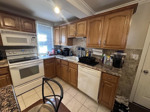 kitchen featuring white appliances, a sink, light tile patterned floors, brown cabinetry, and ornamental molding