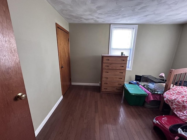 bedroom featuring dark wood-type flooring, baseboards, and a textured ceiling
