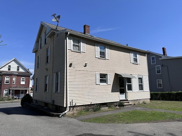 back of property featuring entry steps and a chimney