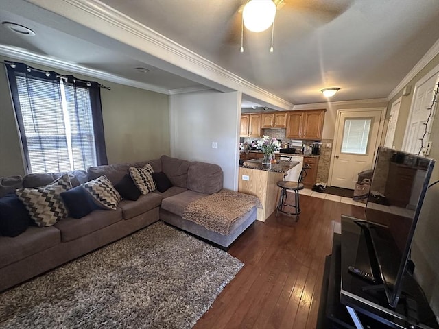 living room with dark wood-style floors, ornamental molding, and ceiling fan