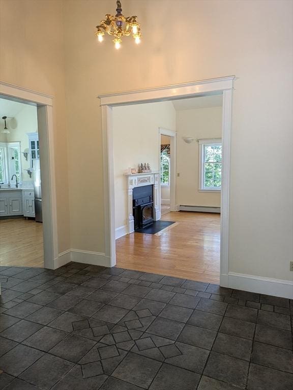 134 Mountain Rd, Princeton, MA 01541 - unfurnished living room with a baseboard radiator, a high ceiling, a chandelier, a sink, and dark wood-style flooring