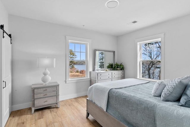 bedroom featuring a barn door and light hardwood / wood-style flooring