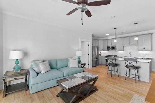 living room with light wood-type flooring, ceiling fan, and crown molding