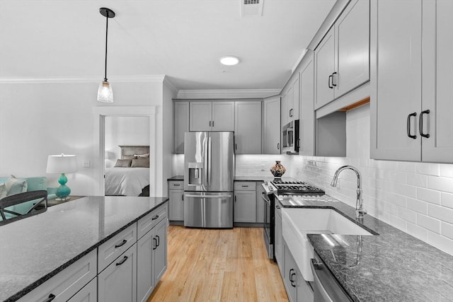 kitchen featuring appliances with stainless steel finishes, light hardwood / wood-style floors, crown molding, pendant lighting, and gray cabinets