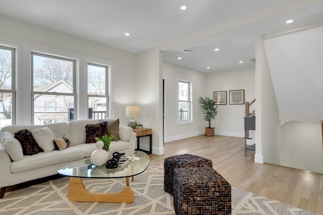 living room featuring baseboards, stairs, light wood-style flooring, and recessed lighting