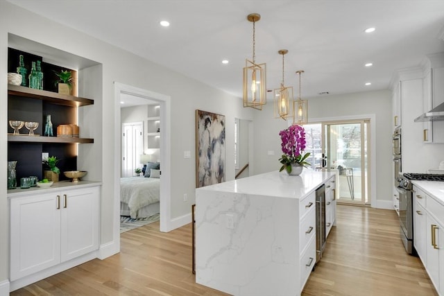 kitchen with recessed lighting, a kitchen island, white cabinetry, light wood-style floors, and stainless steel range with gas cooktop