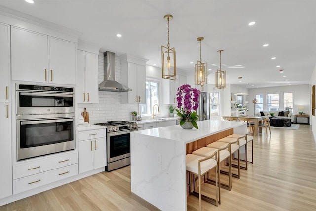 kitchen featuring stainless steel appliances, a kitchen island, open floor plan, wall chimney range hood, and backsplash