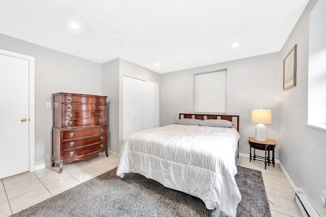 bedroom featuring a closet, light tile patterned floors, and a baseboard heating unit