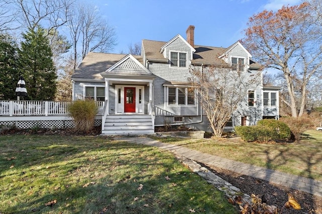 shingle-style home featuring a chimney, a deck, and a front yard