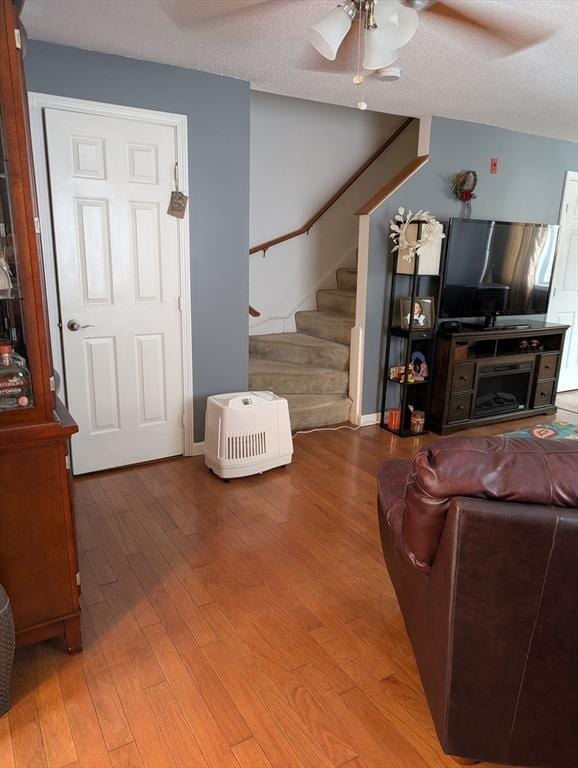 living room with wood-type flooring, ceiling fan, and a textured ceiling