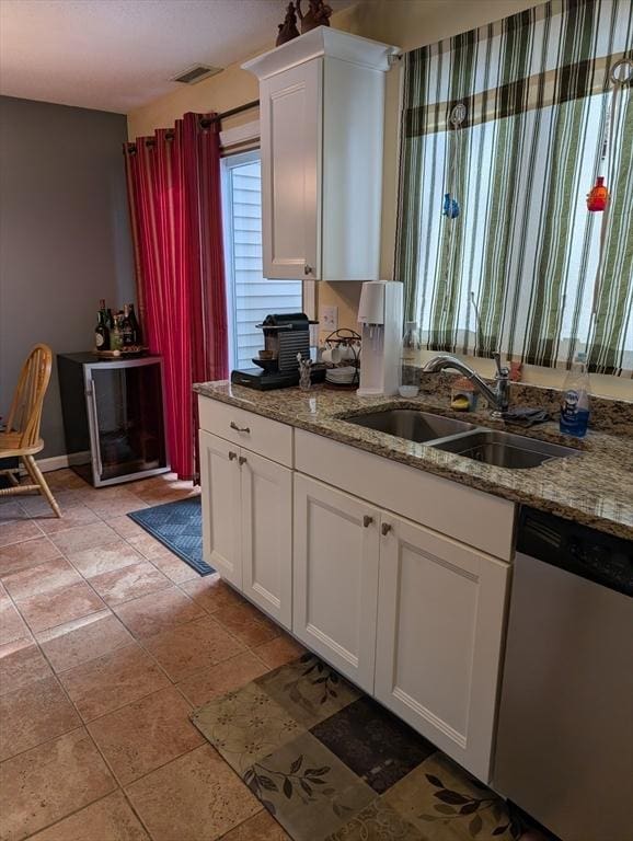 kitchen featuring sink, light tile patterned floors, dishwasher, light stone counters, and white cabinets