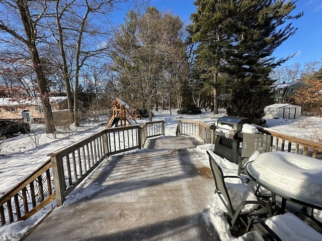 snow covered deck with a grill and a playground