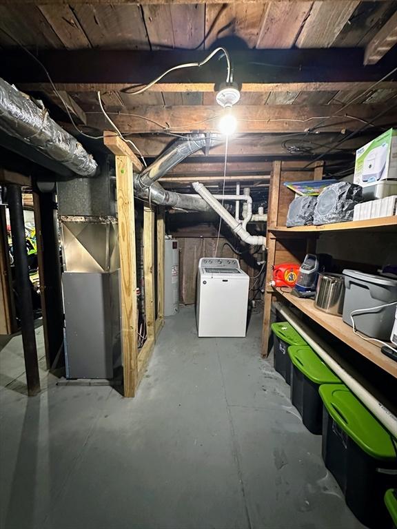 unfinished below grade area with washer / clothes dryer, heating unit, and water heater