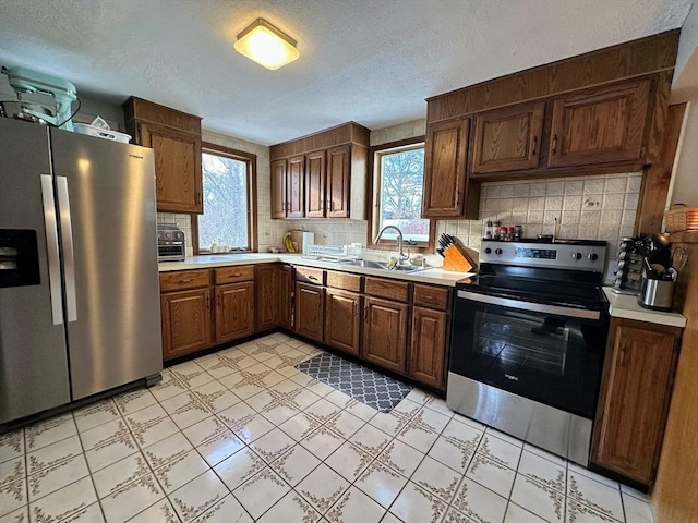 kitchen featuring a sink, light countertops, a wealth of natural light, and appliances with stainless steel finishes