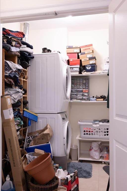 clothes washing area with tile patterned flooring and stacked washer / dryer