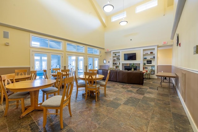 dining room featuring a tile fireplace, a high ceiling, and french doors