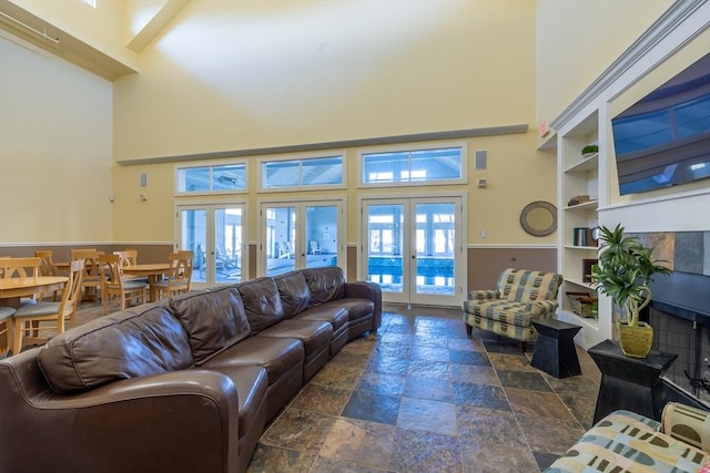 living room featuring french doors, a tiled fireplace, and a high ceiling