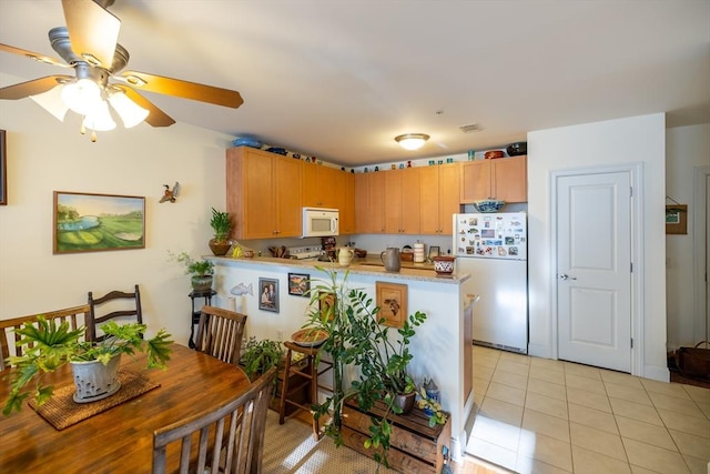 kitchen featuring kitchen peninsula, light tile patterned floors, white appliances, and ceiling fan