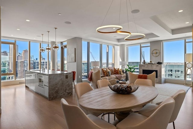 dining area featuring floor to ceiling windows, a fireplace, wood finished floors, a city view, and recessed lighting