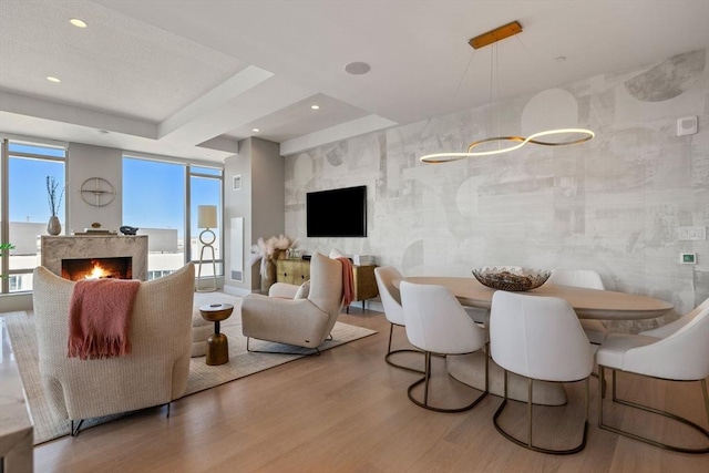 living room with recessed lighting, wood finished floors, and a warm lit fireplace
