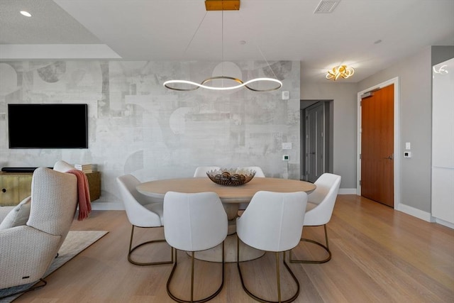 dining area featuring visible vents, baseboards, and wood finished floors