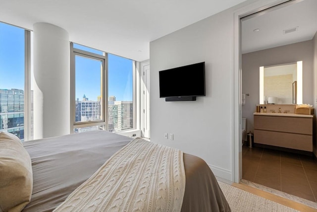 bedroom featuring tile patterned floors, multiple windows, ensuite bathroom, and visible vents