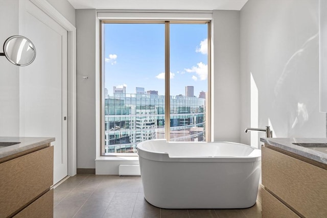bathroom with a freestanding bath, a view of city, vanity, and tile patterned floors